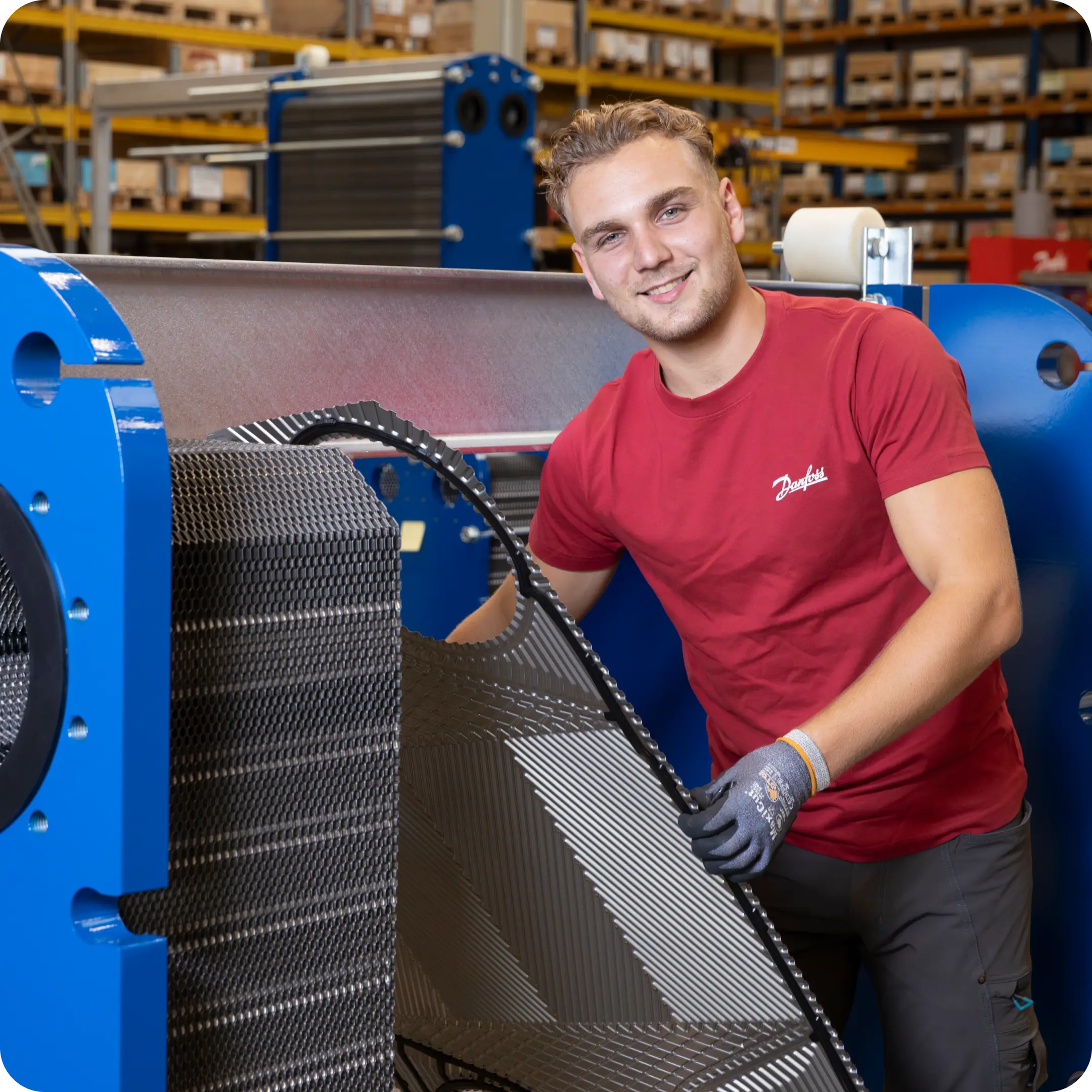 Smiling worker assembling a plate heat exchanger in a warehouse